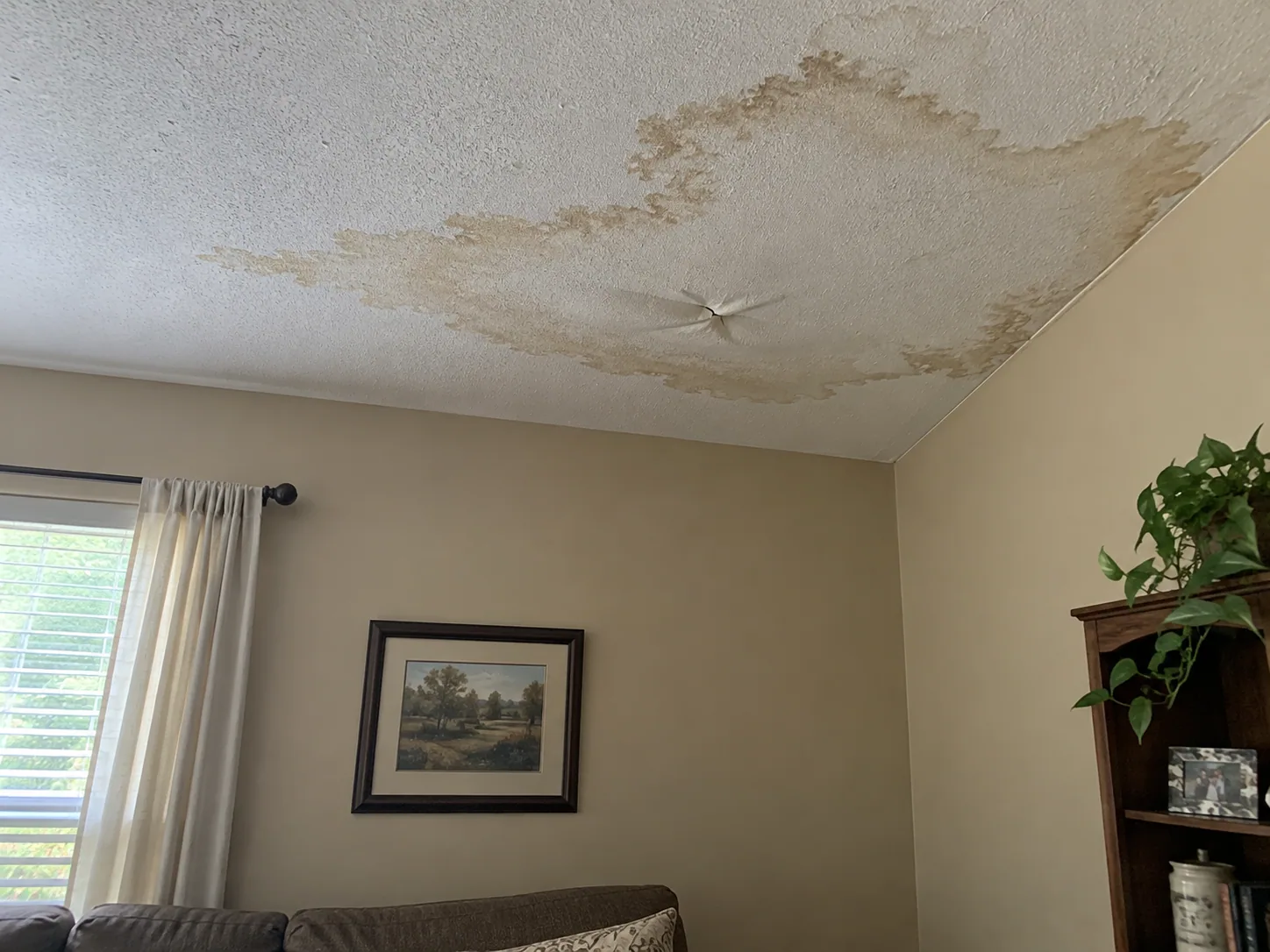 Water stain spreading across a living room ceiling in a Dallas home